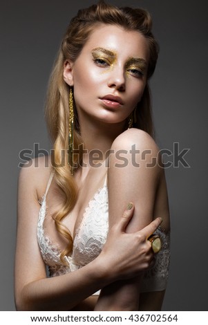 Beautiful girl in Underwear with creative gold makeup and hair. The beauty of the face. Photos shot in the studio.