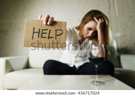 drunk alcoholic blond woman drinking whiskey glass asking for help holding message board depressed wasted and sad at home couch in alcohol abuse and housewife alcoholism Royalty-Free Stock Photo #436717024