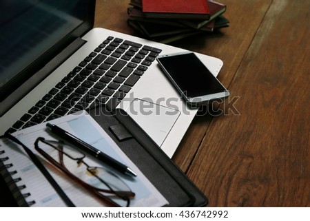 working place with laptop on table,Layout of comfortable working space on wooden, internet laptop headphone phone notepad pen eyeglasses laying on it


