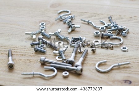 Screw hooks and fasteners made of stainless steel on the wood background.