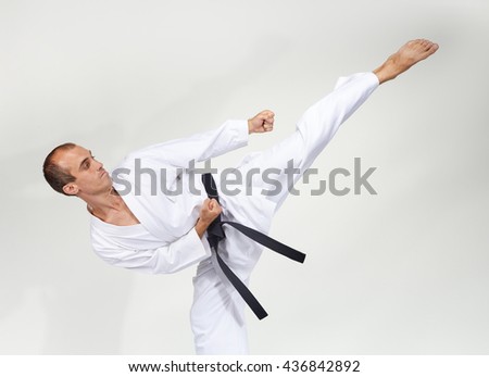 The athlete does a high kick in a white clothes with black belt Royalty-Free Stock Photo #436842892