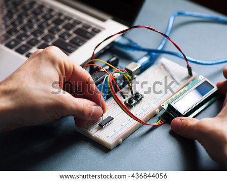 Microchip manual connecting to microcontroller. Top view on engeneer hands working with microcontroller. Closeup of microcontroller Royalty-Free Stock Photo #436844056