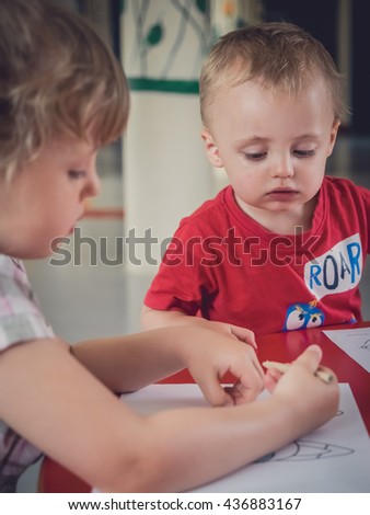 Little kids colouring pictures during art time at the nursery