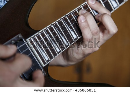 man playing electric guitar close up view, very shallow depth of field image
