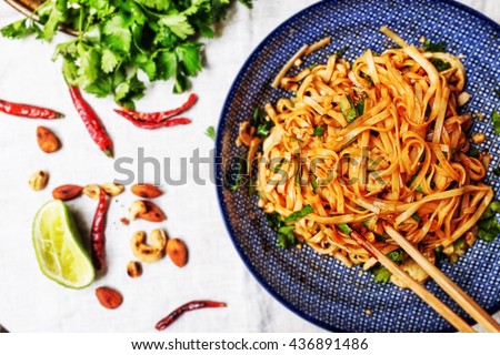Thai style spicy Tom Yum noodle salads with mixed grilled ingredients; champignon, tofu, almonds, cashew, peanut , dried chili and spring chopped coriander, spring onion, soy sauce and chili paste. Royalty-Free Stock Photo #436891486