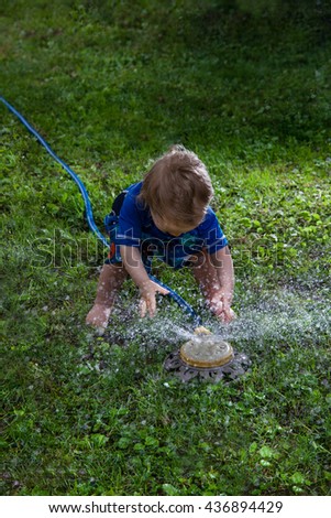 Baby Caucasian Boy playing in his backyard with a garden sprinkler