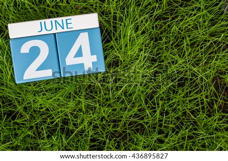 June 24th. Image of june 24 wooden color calendar on green grass lawn background. Summer day, empty space for text.