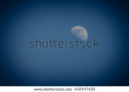 Close-up view of the half-moon at twilight (blue hour) in a clear early summer night without cloud. Vintage look filter.