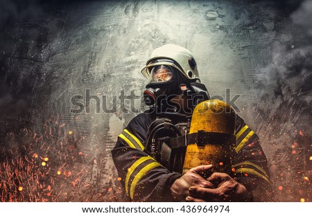 Firefighter in oxygen mask holds yellow oxygen tank.