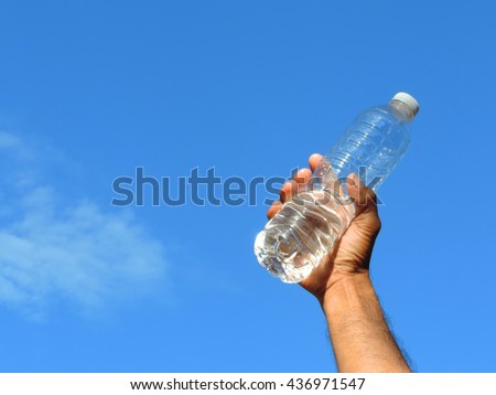 hand holding a bottle of fresh water with blue sky day noon light background.          