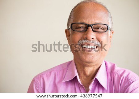 Closeup portrait, smart elderly man in pink shirt with dark eye glasses, specs, sitting down laughing, isolated indoors white chalkboard background Royalty-Free Stock Photo #436977547