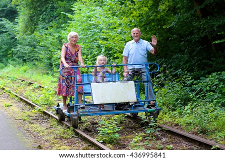 Grandparents with grandchild riding rail-bike on the old railway road. Great leisure activity for family during summer holidays.