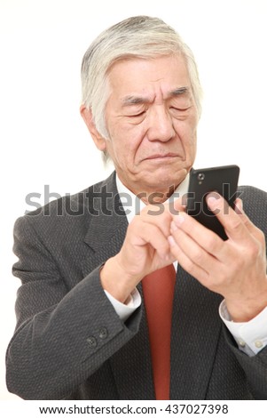 senior Japanese businessman wearing a gray suit  using smart phone looking confused
