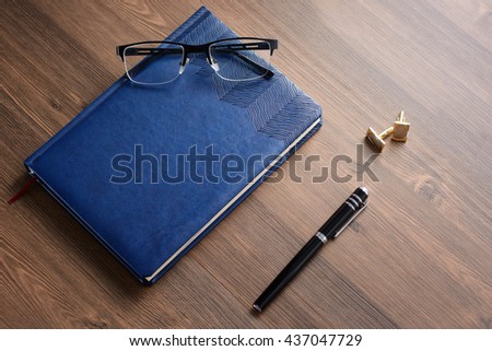 Business accessories on desktop: notebook, diary, fountain pen, cufflinks, glasses. Macro with blur and soft focus. With vignette