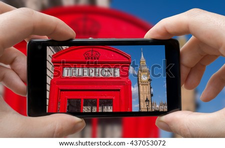 Tourist is taking photo of red phonebooth in London with smartphone.