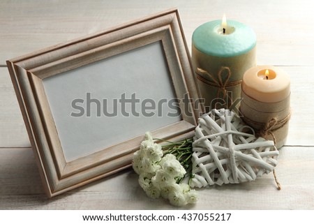 a bouquet of chrysanthemum with wooden frame for photo on wooden background with decorative white heart near the two candles