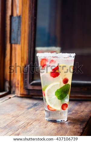 Cold lemonade with strawberry, mint and lemon slice on wooden background. Summer drink. Shallow focus