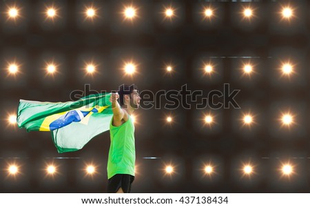 Profile view of Brazilian sportsman is holding a flag against composite image of orange spotlight