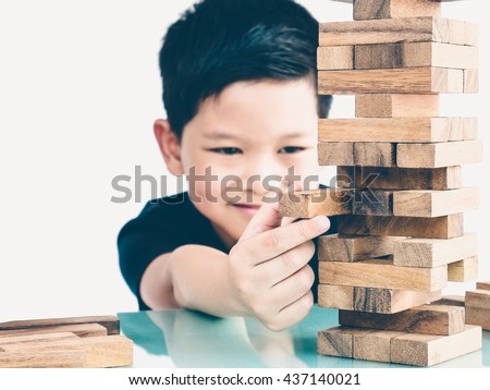 Vintage tone of asian kid is playing wood blocks tower game for practicing physical and mental skill. Photo is focused is hands. Royalty-Free Stock Photo #437140021