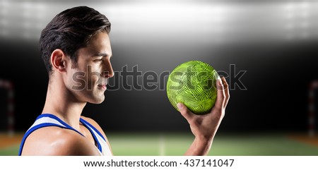 Confident athlete man holding a ball against digital image of handball field indoor