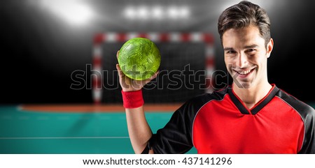Portrait of happy athlete man holding a ball against handball field indoor