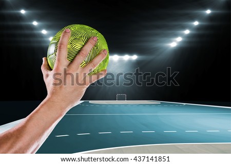 Sportsman holding a ball against handball field indoor