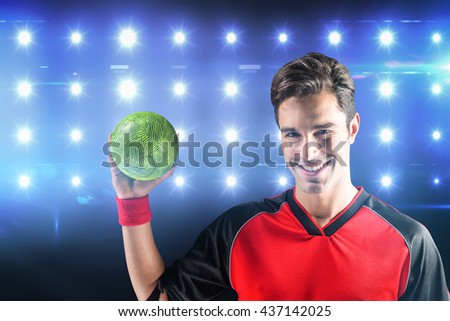 Portrait of happy athlete man holding a ball against composite image of blue spotlight