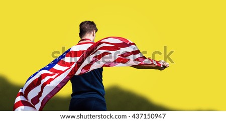 Rear view of sportsman holding an american flag against yellow background