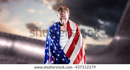 Athlete with american flag wrapped around his body against composite image of arena and cloudy sky