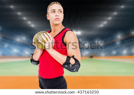 Female athlete with elbow pad holding handball against handball field indoor