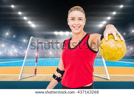 Female athlete with elbow pad holding handball against handball field indoor