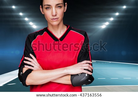 Female athlete posing with elbow pad and crossed arms against handball field indoor