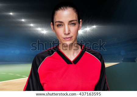 Female athlete posing against handball field indoor