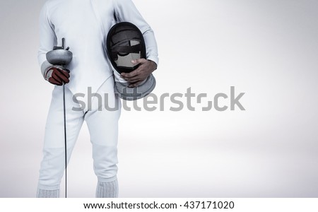 Swordsman holding fencing mask and sword against grey vignette Royalty-Free Stock Photo #437171020