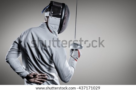 Man wearing fencing suit practicing with sword against grey vignette Royalty-Free Stock Photo #437171029