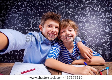 School boy and girl taking selfie against big blackboard