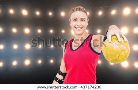 Female athlete with elbow pad holding handball against composite image of orange spotlight