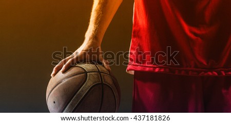 Close up on a basketball held by basketball player on a gym
