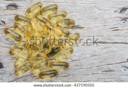 Fish oil supplement capsule over wooden background