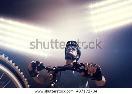 Composite image of man cycling with mountain bike against spotlight