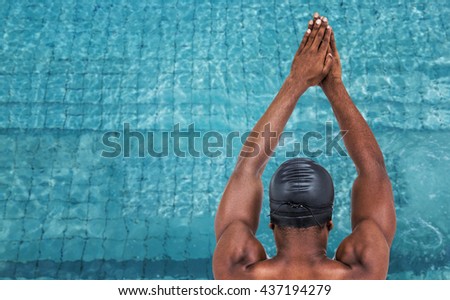 Rear view of swimmer ready to dive against view of swimming pool