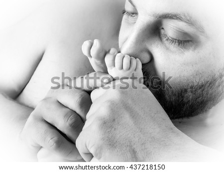 Father kisses the feet of a young child.