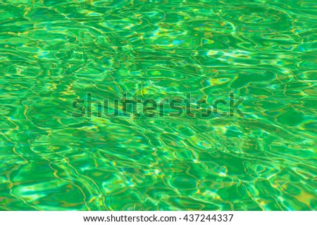 Green water surface with sun reflection in swimming pool