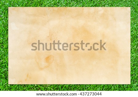 Vintage paper texture background of old brown paper on green grass.