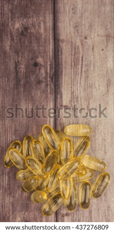 Fish oil supplement capsule over wooden background
