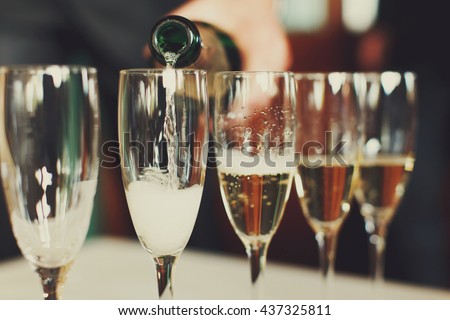 Man pours champagne in wineglasses Royalty-Free Stock Photo #437325811