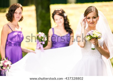Bride looks pretty in her dress while bridesmaids stand on the background