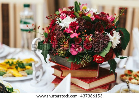 Rich autumn bouquet stands on a red books. Dinner table decoration