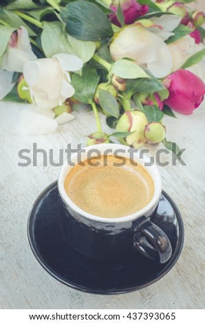 Coffee and flowers peony. A cup of coffee and Peonies on a white wooden table. Breakfast on Mothers day, Valentines Day or Women's day. Spring or summer background. Copy space. Top view. Toned image.