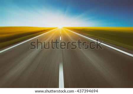 empty asphalt road and floral field of yellow flowers with blur in motion. abstract nature background. vintage picture